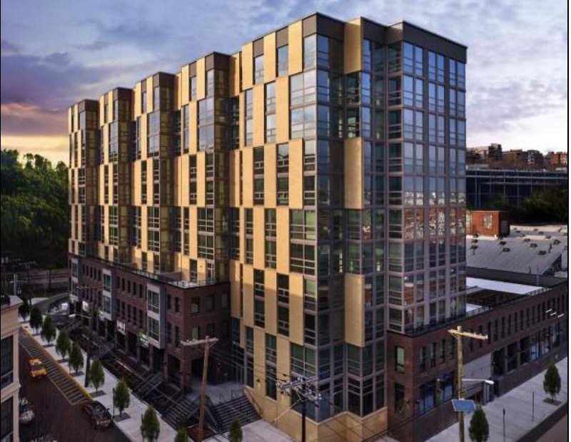 The Vine at dusk, a gold-paneled transit-oriented residential building in Hoboken